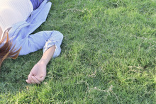 Asian Girl Lay On Grass And Rise Hand Dress In Jeans.