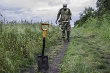 Man In Camouflage Using A Metal Detector