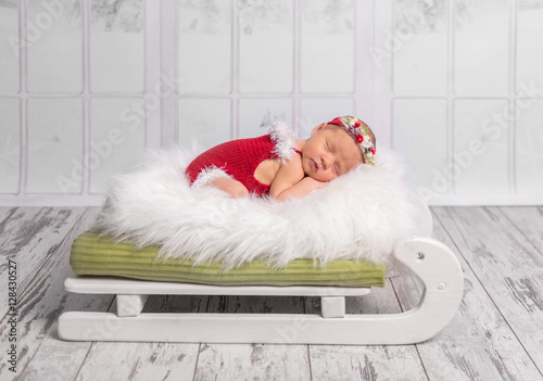 Foto-Schmutzfangmatte - beautiful newborn in red romper on sleigh cot (von tan4ikk)