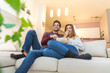 Couple having watching television eating pop corn on the sofa. 
