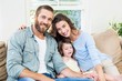 © WavebreakMediaMicro - Portrait of parents sitting on sofa with daughter