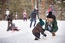 Cute Little Toddller Boy And His Mother Playing With Snow And Making Snowman. Child Having Fun Outdoors In Winter.