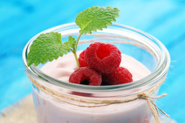 Beautiful appetizer pink raspberries fruit smoothie or milk shake in glass jar with berries background, top view. Yogurt cocktail. Close up. Natural detox. Liquid ice cream. 