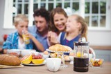 Fototapeta Zachód słońca - Food on table while happy family in background
