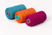 Still Life Of Cyan Orange And Purple Spools Of Thread On A White Background - Closeup Detail