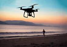 Hovering Drone Taking Pictures Of Runner At The Beach, Sunset
