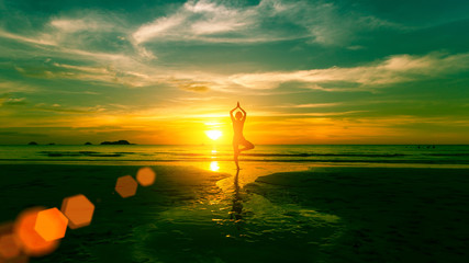 Wall Mural - Young woman practicing yoga on the beach at weird sunset.