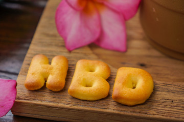 iced coffee and biscuit alphabet spell HBD with rice field backg