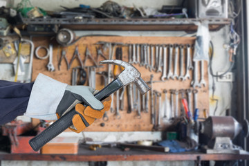 Hand in glove holding hammer with tools hanging