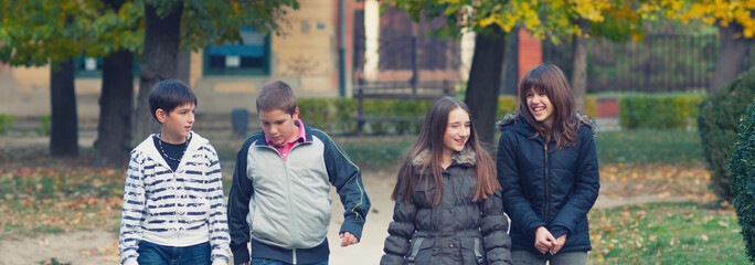 Wall Mural - Happy teenage boys and girl having fun and walking in the autumn park