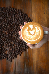 cup of coffee latte art making by barista on old wooden backgrou