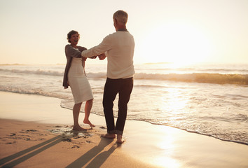 Wall Mural - Smiling senior couple having fun on the beach