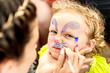 © sushytska - woman painting face of kid outdoors
