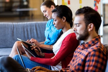 Aufkleber - Colleagues using digital tablet and laptop while sitting on sofa