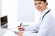 © rogerphoto - Female doctor at the table and filling up medical form. Medicine and health care concept.
