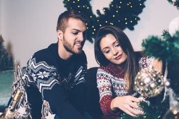 Smiling couple decorating fir tree