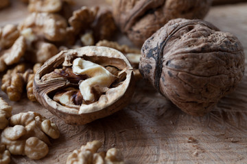 Walnut kernels and whole walnuts on old wooden table, selective