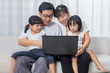 Leinwandbild Motiv Asian Chinese parents and daughters using laptop on the sofa