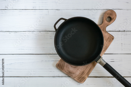 Fotografía Old cast frying pan and cutting board are on the painted white wooden table