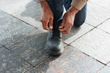Cropped Photo Of Male Hands Tying Shoe Laces On Street