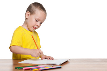 Little boy sits at the desk and write