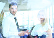 © ASDF - Two cheerful smiling young businesspeople talking at the office. View through window