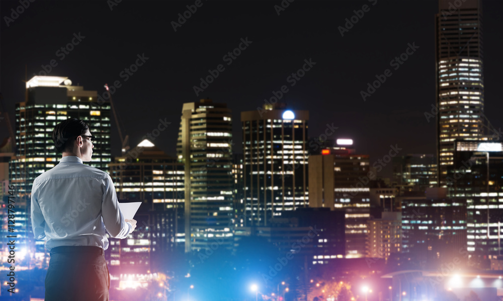 Businessman viewing night glowing city - obrazy, fototapety, plakaty 