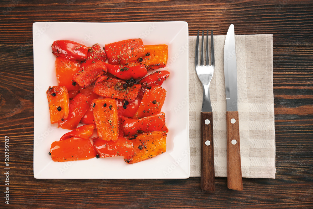 Grilled bell pepper on plate on wooden background, top view