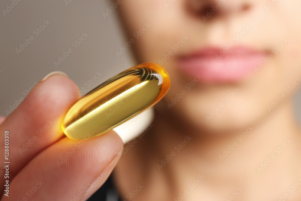 Woman holding Omega 3 fish oil capsule