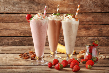 Wall Mural - Delicious milkshakes on wooden background