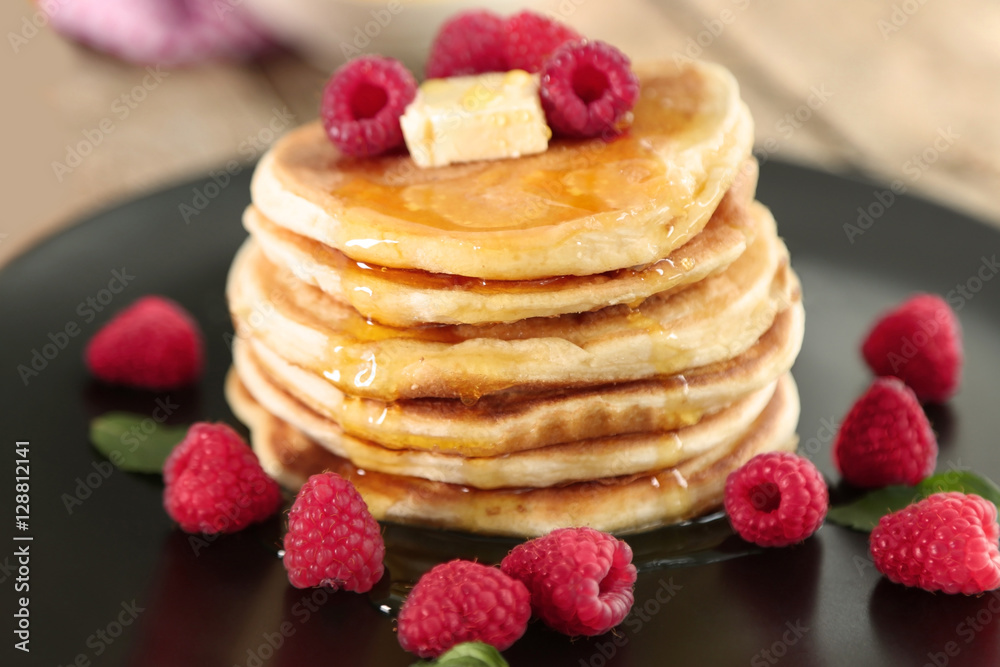 Plate full of tasty pancakes with raspberries