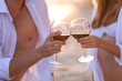 Young happy couple drinking red wine on seashore, closeup