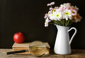 Wall Mural - Bouquet of flowers, book with apple and magnifying glass on wooden table