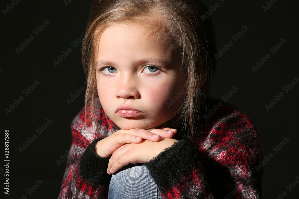 Disappointed little girl on black background, close up view