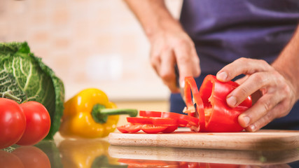  close up of male hand cutting pepper on cutting board