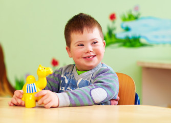 cute kid with down's syndrome playing in kindergarten