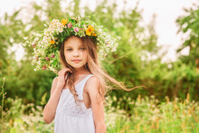Cute Smiling Little Girl  With Flower Wreath On The Meadow At Th