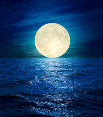 big moon in clouds over night sea