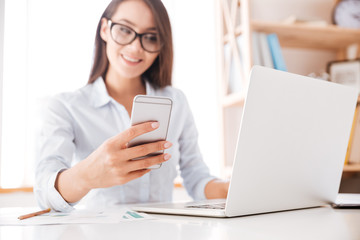 Wall Mural - Cheerful businesswoman looking at phone