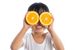 Leinwandbild Motiv Happy Asian Chinese little girl using orange as glasses