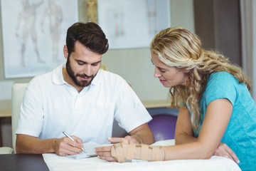 Wall Mural - Physiotherapist writing report next to the patient 