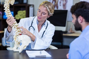 Physiotherapist explaining spine model to patient