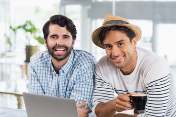 Poster - Portrait of two friends using laptop while having cup of coffee