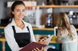 © WavebreakmediaMicro - Portrait of smiling waitress writing in a file