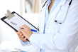 © rogerphoto - Close up of  female doctor  writing a medical prescription at clipboard while standing