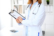 © rogerphoto - Close up of  female doctor  writing a medical prescription at clipboard while standing