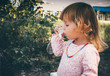 © Mariiam - Baby girl blowing soap bubbles outdoors.