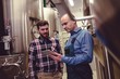 © WavebreakMediaMicro - Worker and owner discussing over digital tablet at brewery