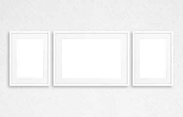 Three blank photo frames mockup on white textured wall