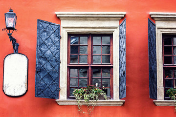 Detail of an open wooden iron vintage rustic windows on red cement old wall can be used for background. Brown black window shutters with decorative flowers